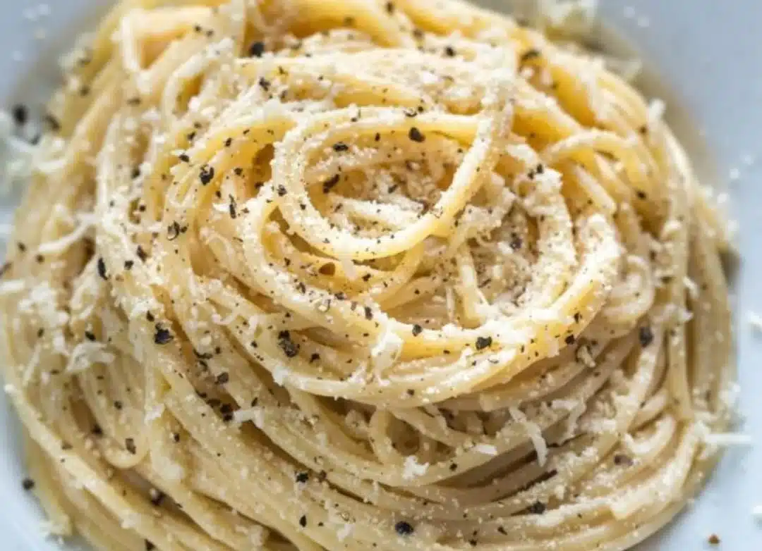 A plate of pasta topped with cheese and pepper seasoning for a flavorful dish